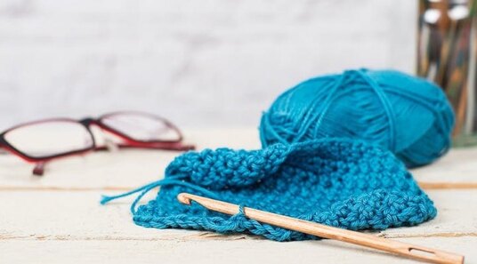 wooden crochet hook and blue yarn on a table