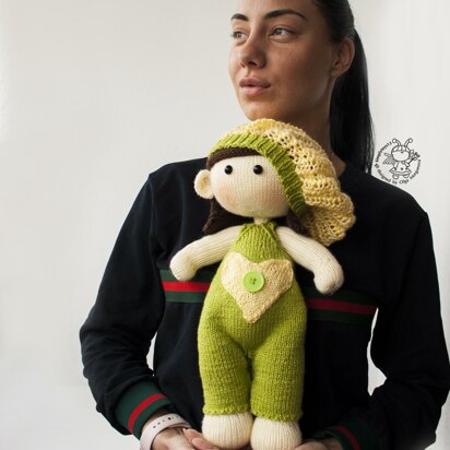 Baby doll in green overalls knitting flat