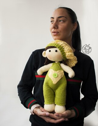 Baby doll in green overalls knitting flat