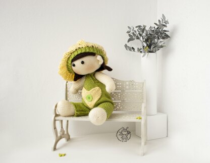 Baby doll in green overalls knitting flat