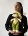 Baby doll in green overalls knitting flat