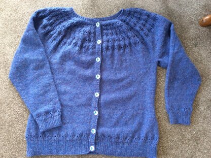 DK cardigan worked seamlessly flat wit lace detail on the yoke and lower body and arms.